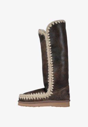 Stivale alto in pelle marrone con finitura testurizzata, caratterizzato da una rifinitura intrecciata color crema lungo il bordo e una robusta suola in gomma per una migliore aderenza.