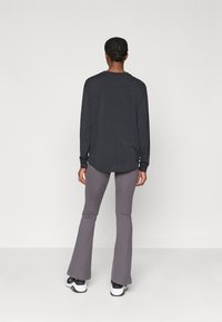 Tumehall pikkade varrukatega pluus, laia lõikega, ümarate servadega. Kombineeritud heledate hallide flared-pükstega ja mustade-valgete pooltöötavate tossudega.