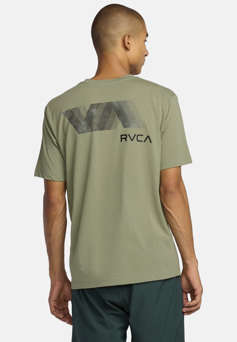 Olive zielona bawełniana koszulka z dużym czarnym logo w formie linii z napisem „RVCA”, krótki rękaw i luźny krój. Widok z tyłu.