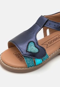 Marin syntetisk sandaler med ett hjärtformat glittrande accent, med turkosa och metallblå remmar, samt en brun vadderad innersula.