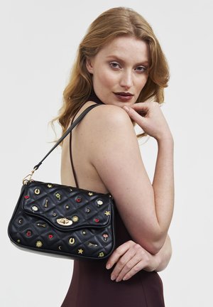 Schwarze gesteppte Lederhandtasche mit einem goldenen Verschluss, verziert mit bunten, bestickten Applikationen, darunter Sterne, Herzen und Blumen.