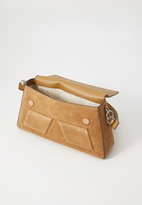 Sac à main en daim marron avec une forme structurée, comportant deux poches avant et un rabat supérieur en cuir. Anse en chaîne avec un détail de couleur accent.