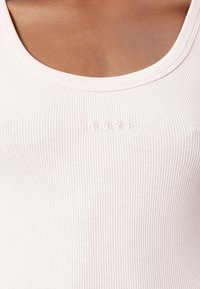 Ribbat tankki vaaleanpunaisena, jossa on pyöreä kaula-aukko. Hieman kohotettu "BOSS" -logo helman lähellä. Pehmeä kangas.