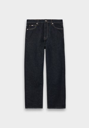 Mørkeblå denimjeans med rett ben-design, fem lommer, kobbernitter og kontrastfarget gul søm på sømmene.