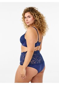 Navy blue lingerie set featuring a lace bralette with adjustable straps and a high-waisted brief with scalloped lace accents and smooth fabric.