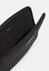 Black fabric pouch with a smooth texture and a zip closure. Features a logo tag inside and a spacious, unlined interior.