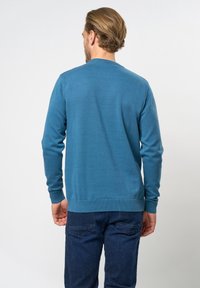 Niebieski sweter z okrągłym dekoltem i długimi rękawami, z prążkowymi mankietami i krawędzią, wykonany z gładkiej dzianiny. Widok z tyłu nie pokazuje widocznych wzorów.