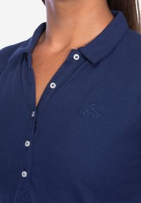 Navyblauwe polo met een gestructureerde stof, knoopsluiting en een subtiel logo op de borst. Voorzien van een klassiek kraagontwerp.