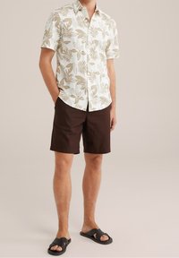 Short-sleeve, white shirt with brown leaf pattern; paired with brown shorts and black sandals. The material appears lightweight and casual.