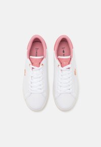 Paire de baskets basses blanches avec doublure intérieure rose, lacets blancs et logo Lacoste en or rose sur le côté et la languette.