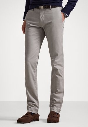 Lys grå chinos lavet af bomuld, med en slim fit, glat tekstur, sidelommer og et minimalistisk design. Båret med brune ruskind loafers.