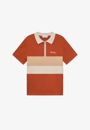 Trumpas rankovės polo marškinėliai degančios oranžinės spalvos su kremine apykakle ir horizontaliu bežiniu dryžiu. Yra priekinis užtrauktukas ir išsiuvinėtas logotipas.