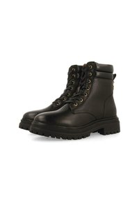 Botas de tobillo de cuero negro con punta redonda, cordones en el frente, ojales dorados, cuello acolchado y suela de goma gruesa. Cuenta con un logo en el lateral.