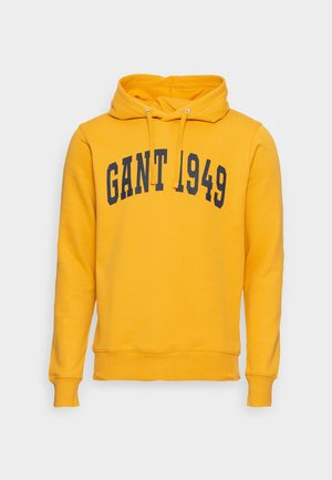 Gul hoodie av bomull med kenguruficka, dragsko i huvan och "GANT 1949" tryckt i mörkblått över framsidan.