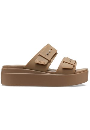 Jasnobrązowe sandały na platformie wykonane z elastycznego materiału, z dwoma szerokimi paskami. Posiadają trzy dekoracyjne ćwieki oraz teksturowaną wkładkę dla komfortu.
