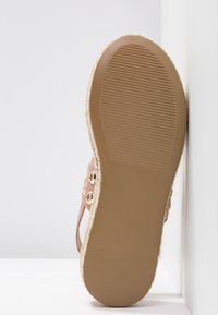 Sandale espadrille rose avec une semelle enveloppée de jute, une semelle extérieure en caoutchouc antidérapante et des œillets métalliques décoratifs sur les brides.