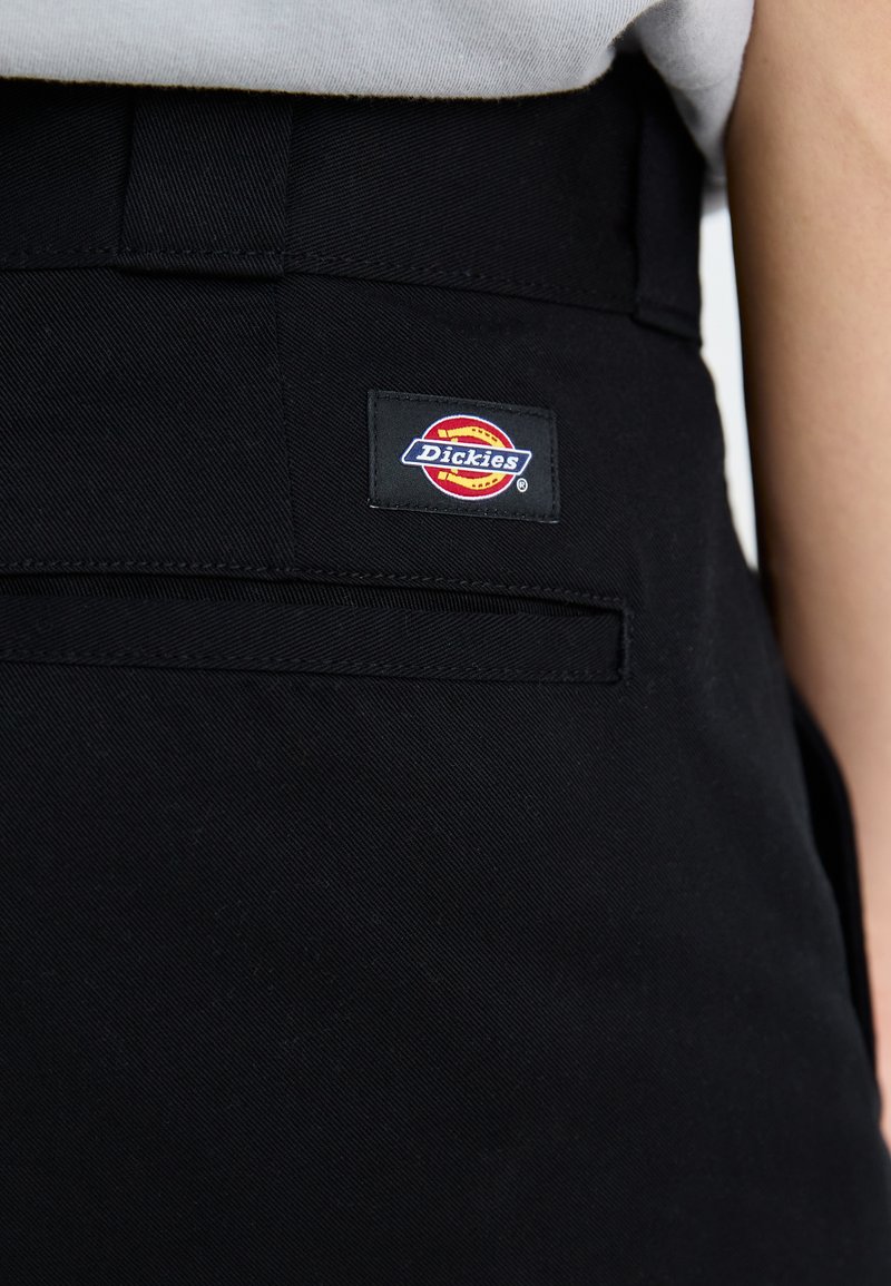 Schwarze Hose aus strukturiertem Material, mit einer Gesäßtasche und einem bunten "Dickies"-Logopatch. Schlichtes, funktionales Design.