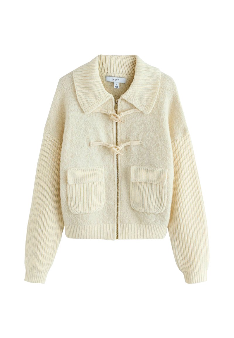 Cream-colored cardigan with a textured body, ribbed sleeves, large pockets, and toggle closures. Features a wide, round collar and zipper.