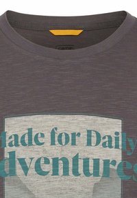 Grå T-shirt med rund hals, fremstillet i et struktureret stof. Forsiden viser et grafik med teksten "Made for Daily Adventures" i teal.