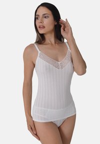 White camisole with lace detailing at the neckline, featuring vertical stripes, thin straps, and a semi-sheer textured fabric.