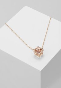 Collier en or rose avec un design floral mettant en avant une pierre rose centrale entourée de petites pierres claires sur une chaîne délicate.
