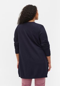 Marineblå långärmad cardigan med en avslappnad passform, ribbade manschetter och rak nederkant. Slät stickad material, ventilerad ryggdetalj.