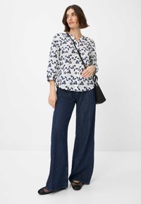 Blomstret bluse i hvid og marineblå, med trekvartærmer og knaplukning. Sammen med vide mørkeblå jeans og sorte sko.
