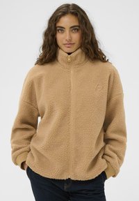 Beez fleece-jakk, millel on kõrge krae, täis tõmblukk ja elastsed mansetid. Omab tekstuurset pinda ja minimaalset brändingut rinnal.