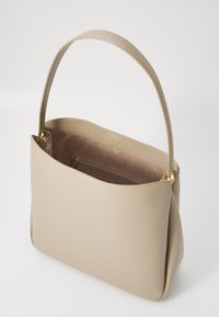 Beige leather handbag with a smooth texture, featuring a single handle and a zippered inner pocket, showcasing minimalist design elements.