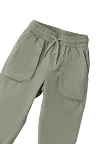Jasnozielone spodnie z elastycznym paskiem w talii i regulowanym sznurkiem; mają duże boczne kieszenie i gładki, lekko teksturowany materiał.