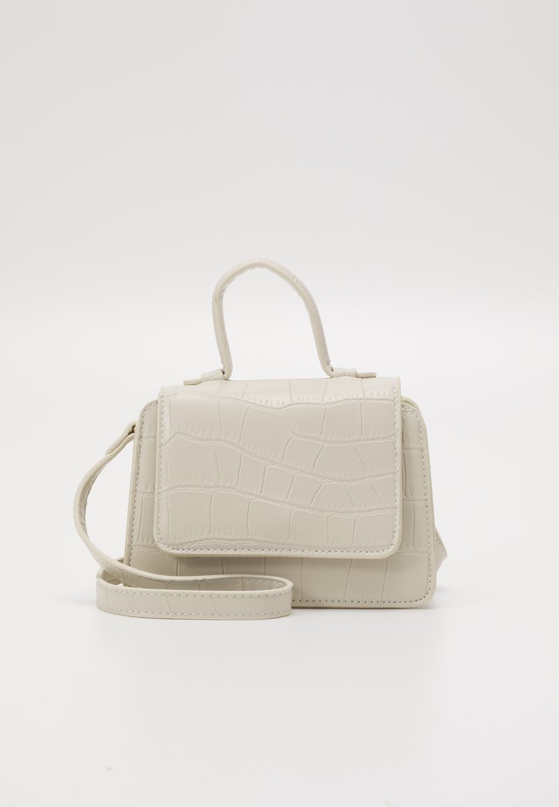 Beżowa torebka w wzór krokodyla z górnym uchwytem i odczepianym paskiem na ramię. Posiada zapięcie na klapkę oraz usztywniony kształt.