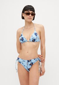 Blå blommig bikiniuppsättning med triangeltopp och justerbara axelband samt låg midjeblåsa med side ties. Strukturerad tyg med blommönster.