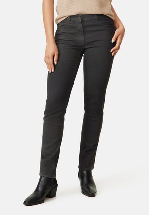 Black skinny jeans made from denim, featuring a mid-rise waist, slim fit, and front pockets, paired with black ankle boots.