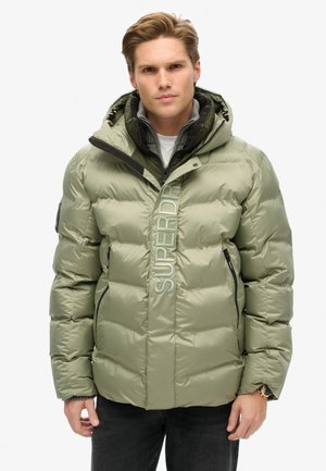 Veste rembourrée vert olive avec capuche. Dotée d'une fermeture éclair à l'avant, de poches latérales et d'un logo sur le devant. Texture du tissu lisse et brillant.