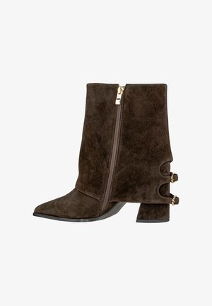 Botines de ante marrón con punta afilada, cremallera lateral y detalles en dorado. Presentan un elegante tacón cuadrado y recortes decorativos.