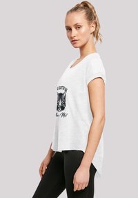 White short-sleeve T-shirt with a round neckline, featuring a black cat graphic wearing sunglasses and text beneath it. Hem is slightly longer at the back.