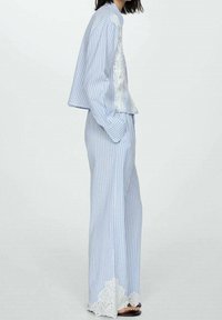 Raidallinen sinivalkoinen puuvillavaatetus, jossa on lyhyt toppi brodeerauksella ja leveät housut pitsireunalla.