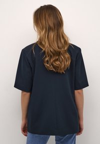 Camisa de manga corta, color azul marino, con un corte holgado, fabricada en una tela suave, con un dobladillo recto y un diseño minimalista.
