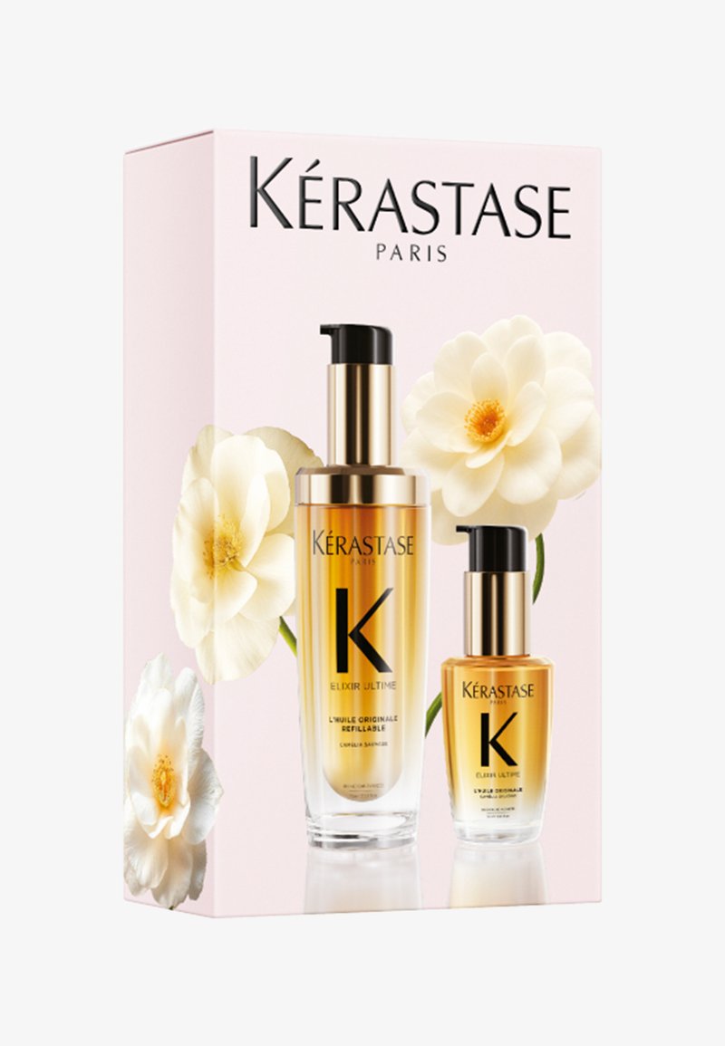 Kérastase Paris Elixir Ultime haarolie set met pompflessen in goud en helder glas, tentoongesteld op een lichtroze doos met witte bloemen.