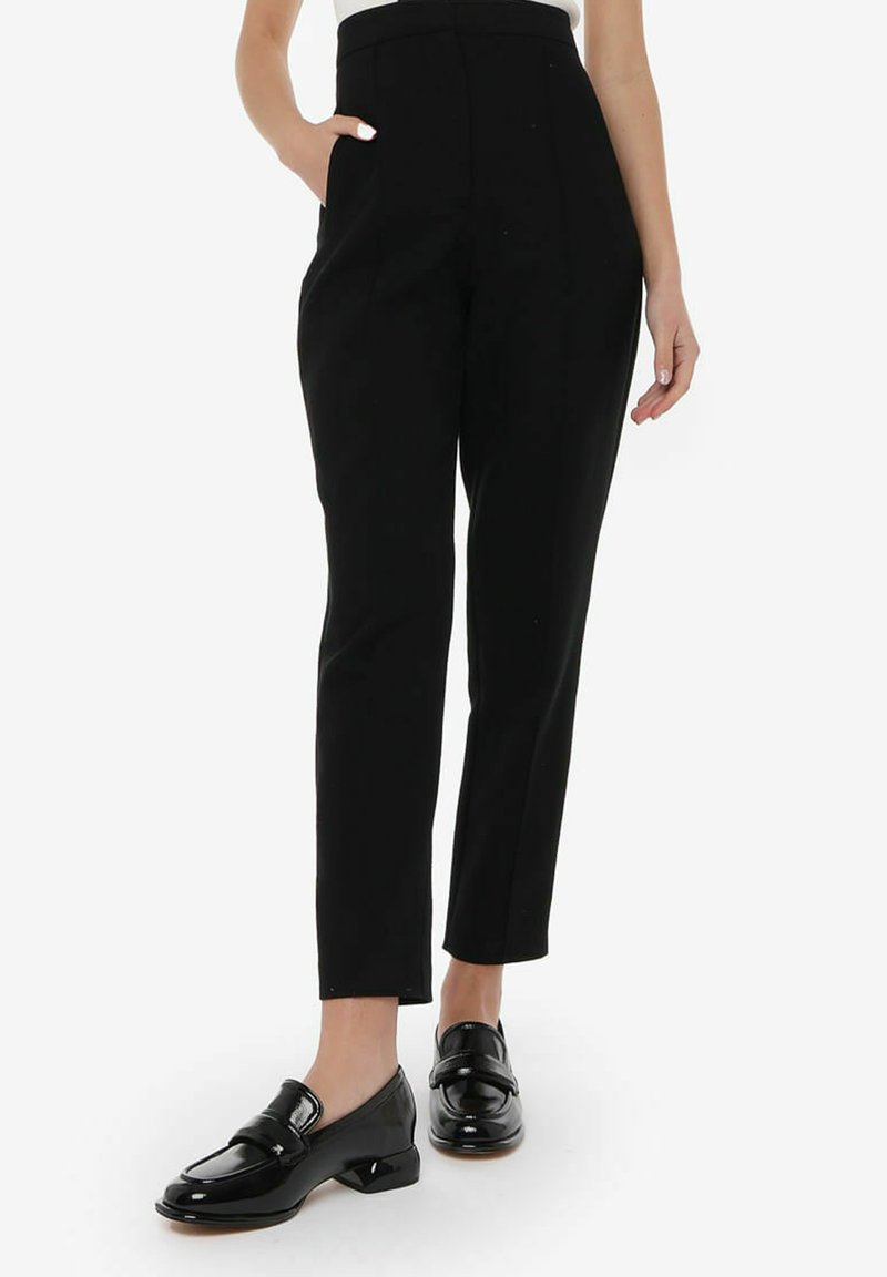 Zwarte op maat gemaakte broeken met een hoge taille, slim fit, zijzakken en een soepele stoftextuur. Gecombineerd met glanzende zwarte instappers.