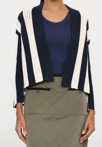 Cardigan v háčkovaném stylu s námořnickými a krémovými pruhy, otevřený vpředu, volný střih, kombinovaný s přiléhavým námořnickým topem a zelenou prošívanou sukní.