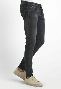 Jeans slim en denim gris foncé. Les caractéristiques comprennent un design traditionnel à cinq poches, un léger délavage et une quincaillerie de fermeture éclair jaune.