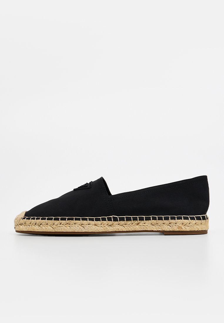 Espadrille de lienzo negro con suela de yute, que presenta una punta redondeada y un diseño minimalista. Textura suave, perfil plano.