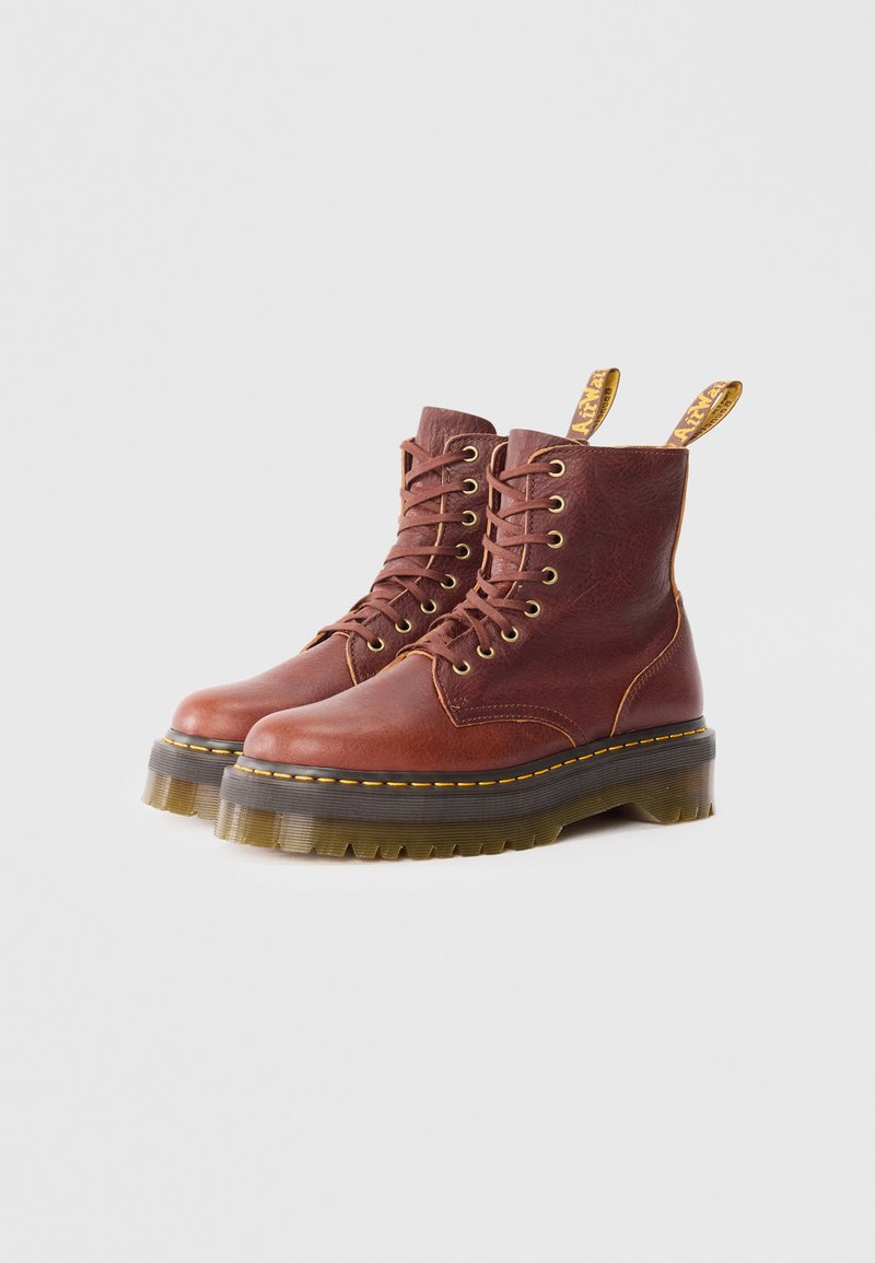 Bottines en cuir marron à lacets avec une semelle en caoutchouc épaisse, des coutures jaunes et des tirettes à l'arrière. Fini texturé et hauteur mi-mollet.