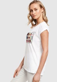 White cotton t-shirt with short sleeves featuring a colorful graphic of eyes in three panels and a speech bubble text. Casual fit.