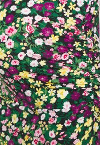 Kwiecista sukienka na czarnym tle ma marszczoną teksturę; multikolorowe kwiaty w odcieniach różu, fioletu, żółci i bieli rozmieszczone na całej tkaninie.