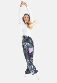 Jeans s patchwork dizajnom a poškodenými detailmi, s ružovým srdiečkom ako akcentom. V kombinácii s bielym topom s dlhým rukávom a bielymi teniskami.