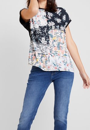 Haut à manches courtes à motifs floraux avec une partie supérieure noire et des motifs floraux pastel en bas. Tissu doux, léger, coupe décontractée.