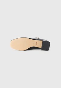 Black leather shoe sole featuring a smooth finish, a slight heel, and a contrasting brown outsole with embossed branding detail.