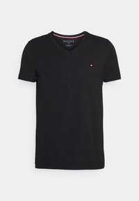 T-shirt in cotone nero con scollo a V, maniche corte e un piccolo logo sul petto. Texture liscia e design casual.